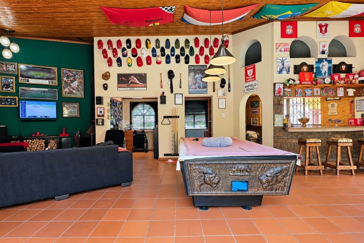 Spacious living and entertainment area featuring a timber-clad ceiling, terracotta flooring, and a built-in bar with arched architectural wall niches.