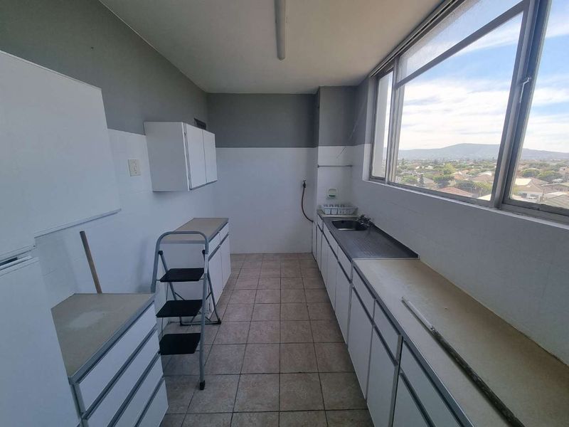 A functional scullery or utility area featuring built-in cabinetry, a stainless steel sink, and large windows offering expansive views.