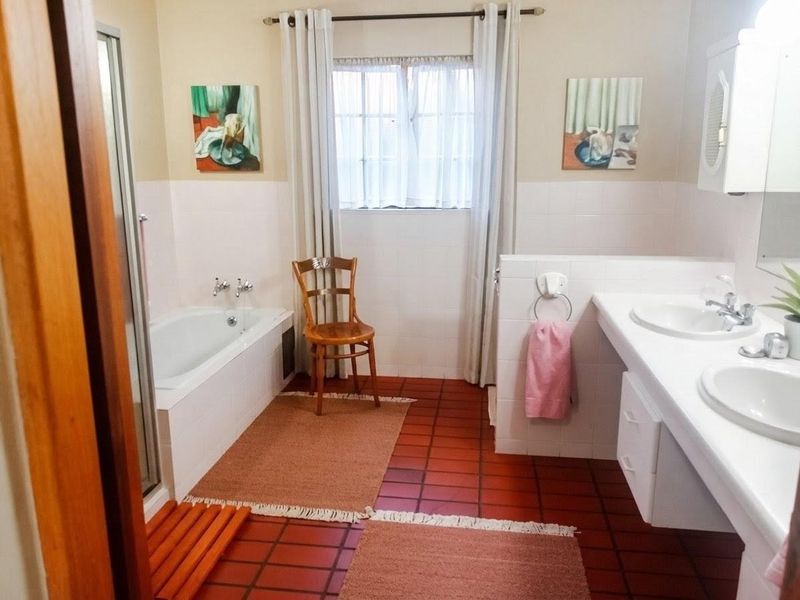 A functional bathroom featuring a built-in bathtub, a double vanity with dual sinks, and tiled flooring throughout.