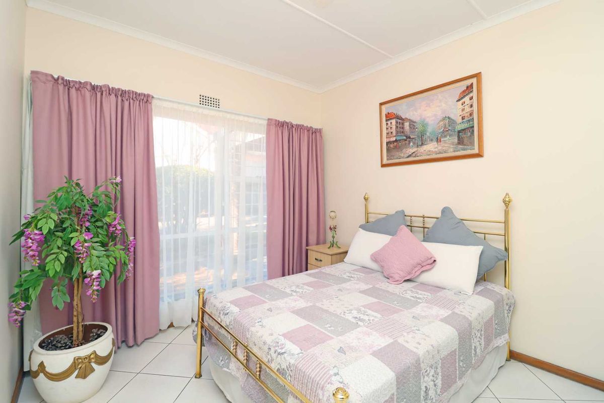 A well-lit bedroom featuring tiled flooring and a sliding glass door providing access to the exterior.