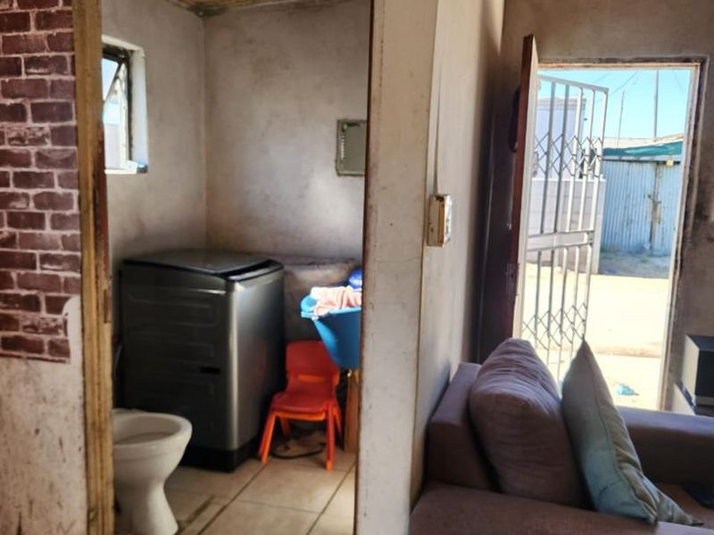 A functional laundry area featuring tiled floors and timber ceiling, adjacent to the main living space with direct access to the exterior.