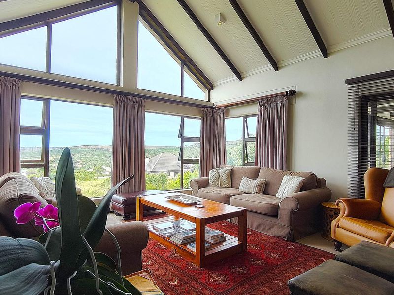 Spacious living room featuring a high vaulted ceiling with exposed timber beams and expansive windows offering scenic views.