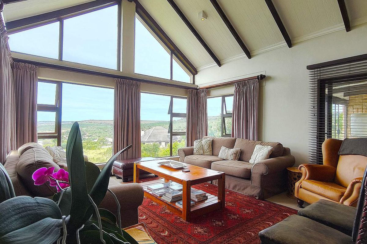 Spacious living room featuring a high vaulted ceiling with exposed timber beams and expansive windows offering scenic views.
