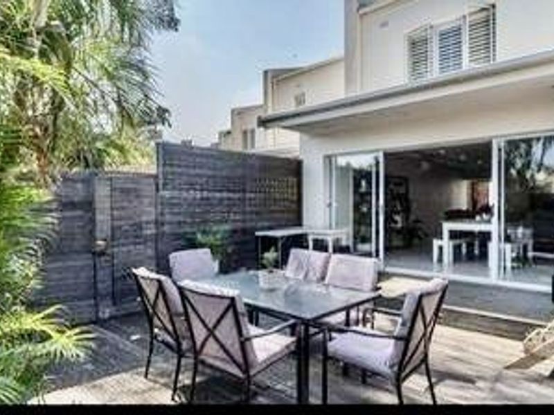 A covered outdoor patio featuring timber decking and large sliding glass doors that provide seamless access to the interior living space.