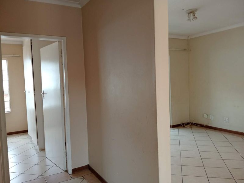 An empty hallway area featuring tiled flooring and neutral wall finishes, providing access to adjacent rooms within the apartment.