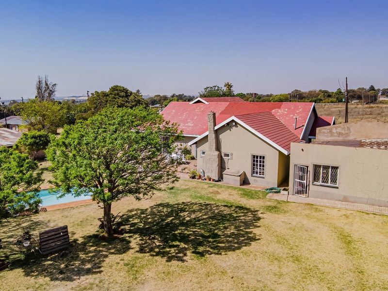 Aerial view of the small holding property featuring a main dwelling with a pitched roof, a swimming pool, and surrounding garden space.