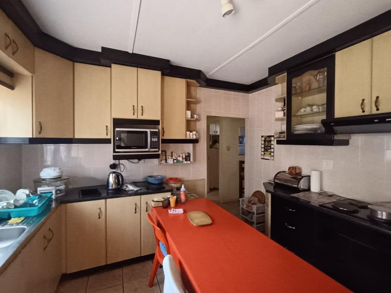 A functional kitchen featuring built-in cabinetry, laminate countertops, and integrated appliances, offering a practical layout with potential for modern cosmetic updates.