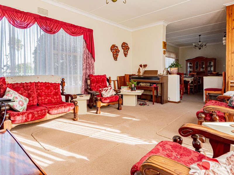 Spacious open-plan living and dining area featuring timber wall paneling, neutral carpeting, and large windows allowing for ample natural light.