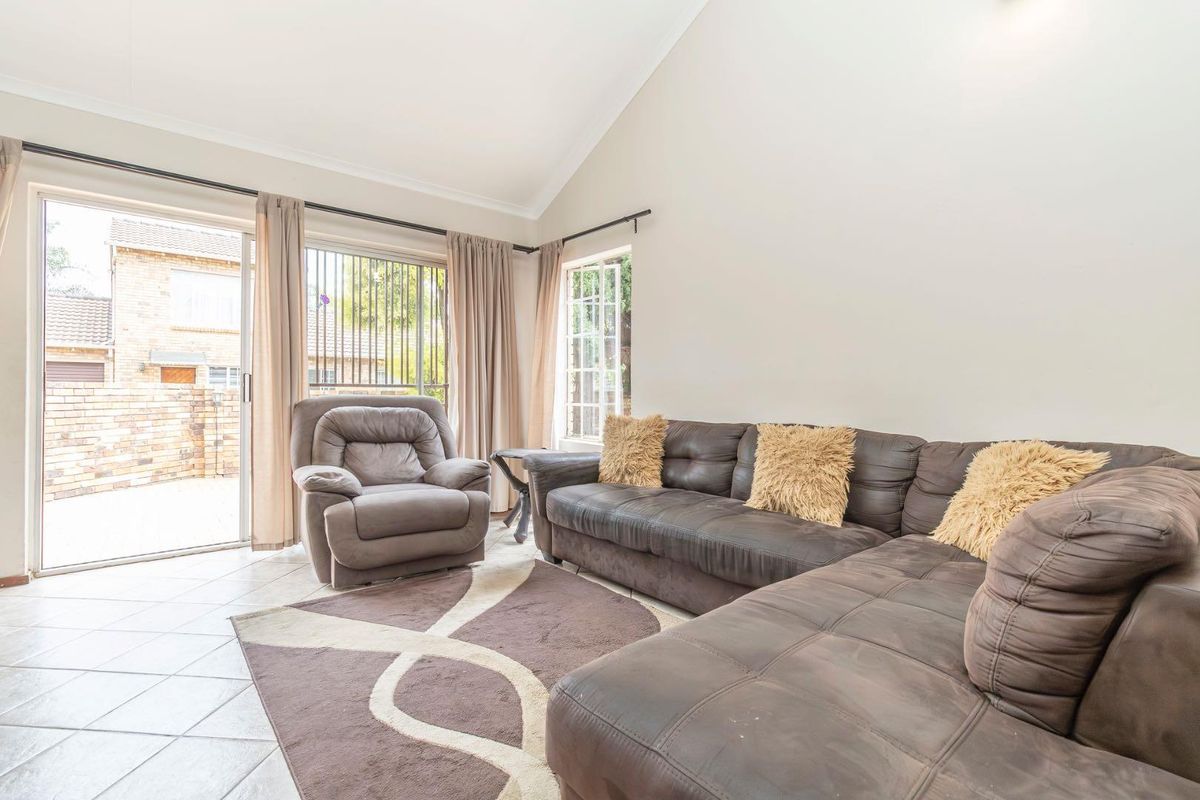 Spacious living room featuring high vaulted ceilings, tiled flooring, and large sliding glass doors providing direct access to the outdoor area.