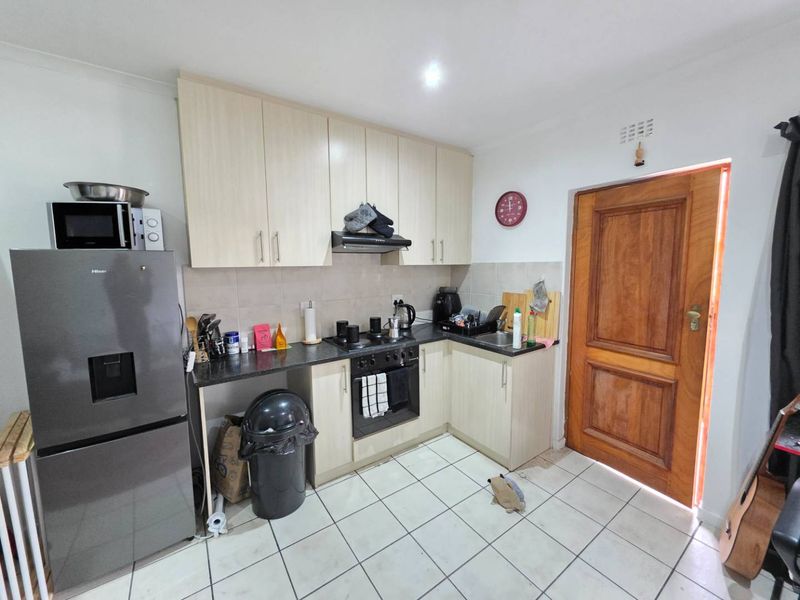 Functional kitchen featuring light-toned cabinetry, dark laminate countertops, built-in oven with extractor fan, and tiled flooring, providing a practical workspace.