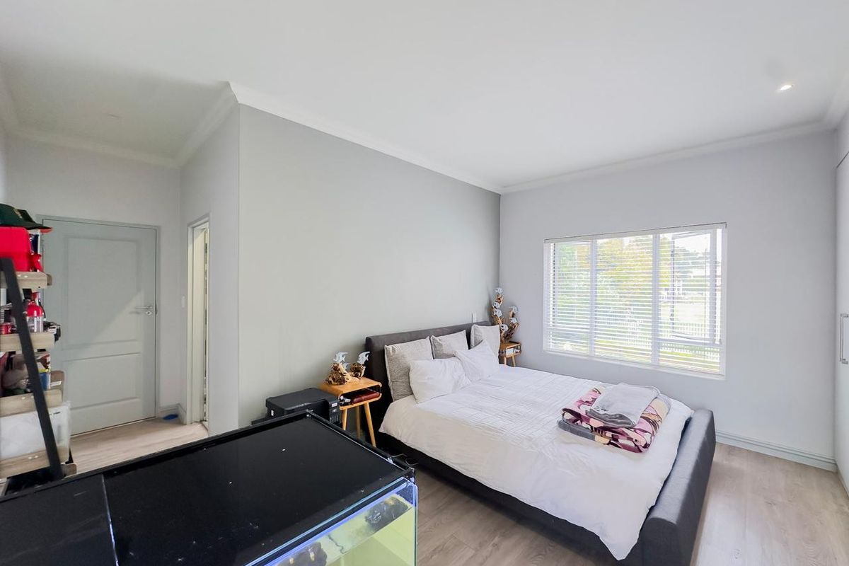 A bright and well-maintained bedroom featuring light wood-look flooring, neutral wall tones, and built-in wardrobe storage.