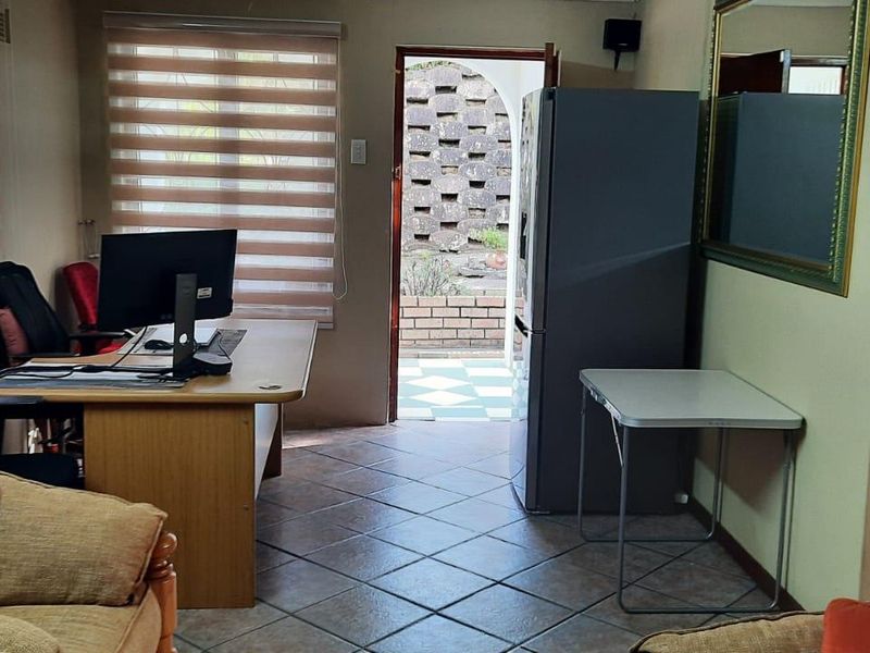 A living area featuring tiled flooring and zebra blinds, with direct access to an outdoor patio area.