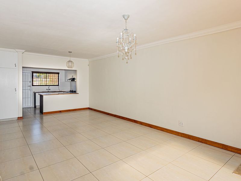 Spacious open-plan living area featuring tiled floors, a wood-burning stove, and a functional kitchen with built-in cabinetry and an extractor fan.