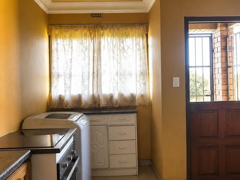 A functional kitchen featuring built-in cabinetry, a built-in oven with hob, tiled flooring, and a timber ceiling, with direct access to an exterior area.