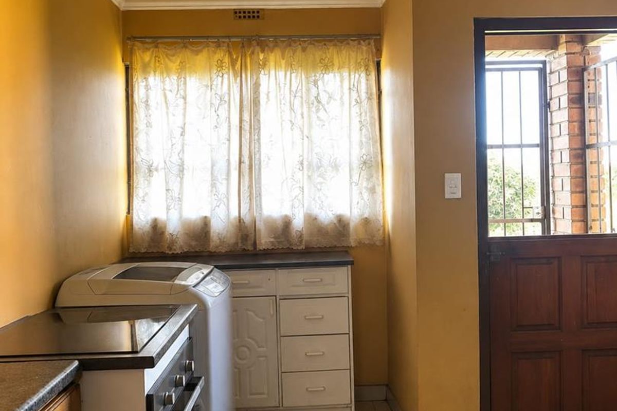 A functional kitchen featuring built-in cabinetry, a built-in oven with hob, tiled flooring, and a timber ceiling, with direct access to an exterior area.