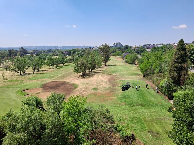 Elevated panoramic view overlooking a lush green golf course with mature trees and landscaped fairways.