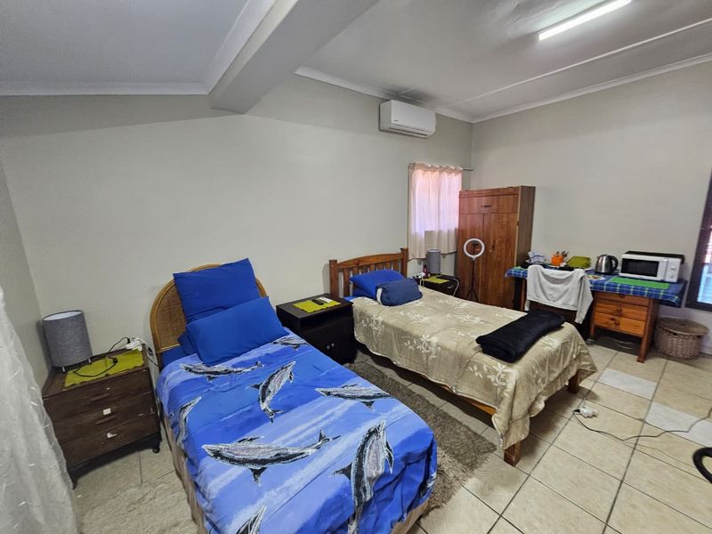 A functional bedroom featuring tiled flooring and a wall-mounted air conditioning unit.