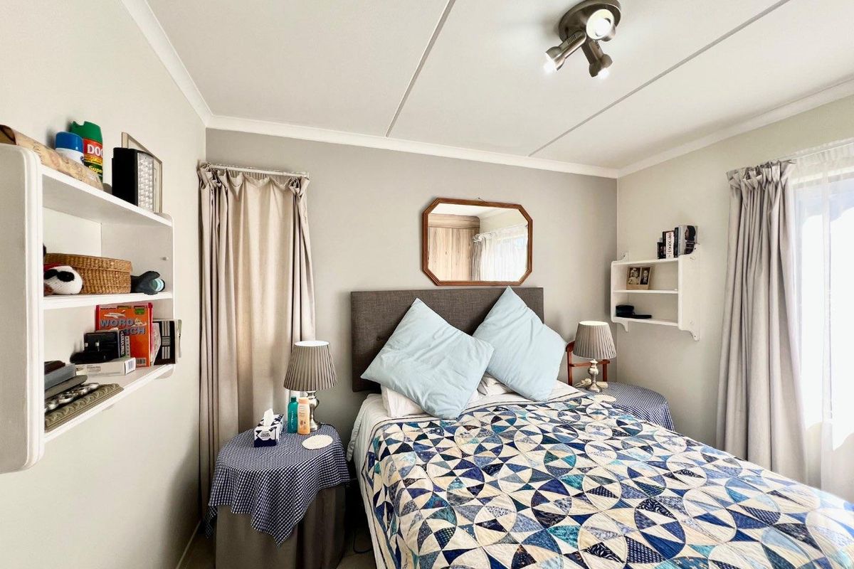 A functional bedroom featuring tiled flooring, built-in wall shelving, and a ceiling-mounted spotlight fixture.