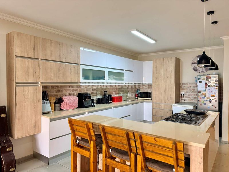 Modern kitchen featuring light wood and white cabinetry, stone countertops, a gas hob, and a decorative brick-style backsplash.