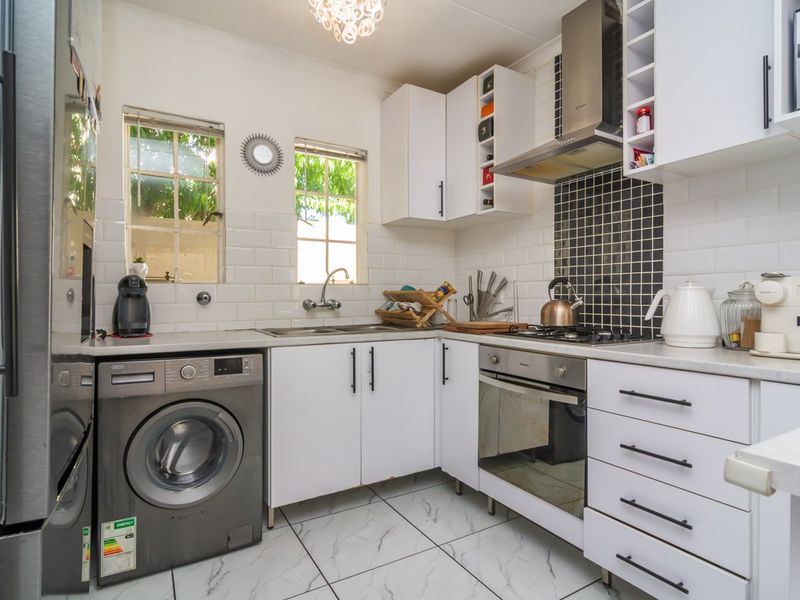 Compact kitchen featuring white cabinetry, subway tile backsplash, mosaic feature wall, built-in oven, gas hob, and marble-look floor tiles.