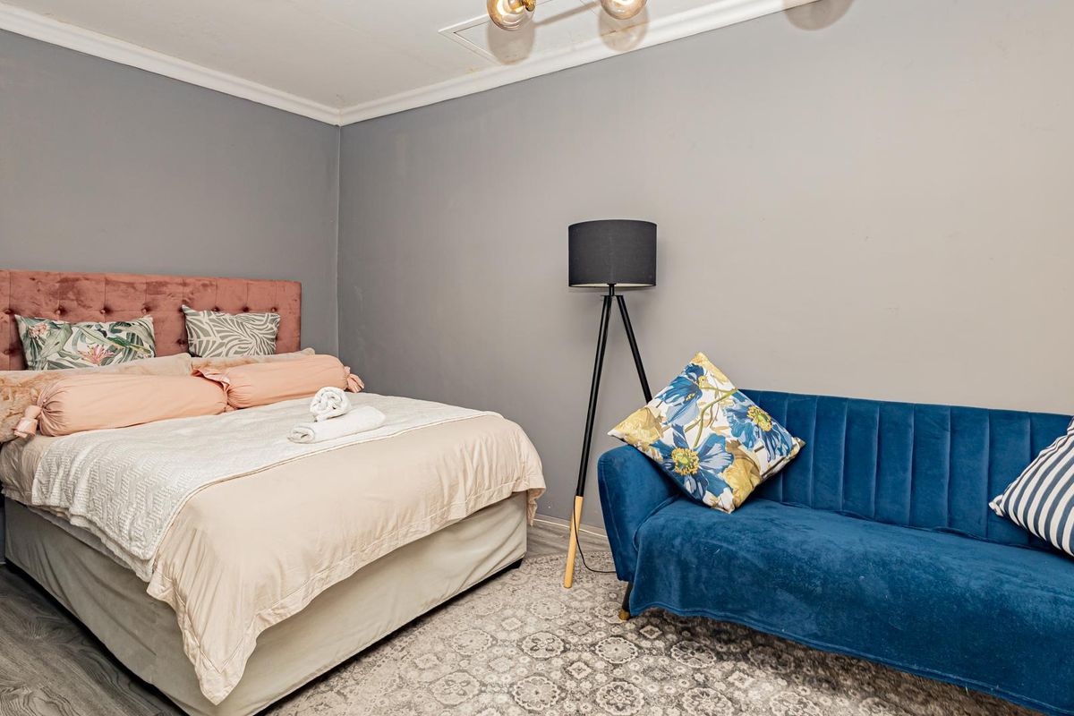 A well-maintained bedroom featuring grey walls, cove cornicing, and durable laminate flooring, providing a comfortable and neutral living space.