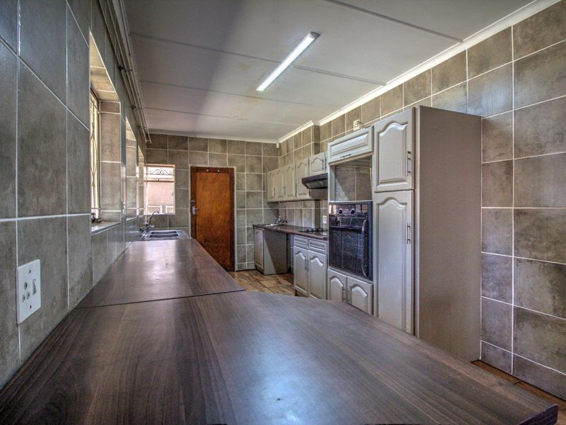A functional kitchen featuring built-in cabinetry, laminate countertops, a built-in oven, and tiled wall finishes throughout.