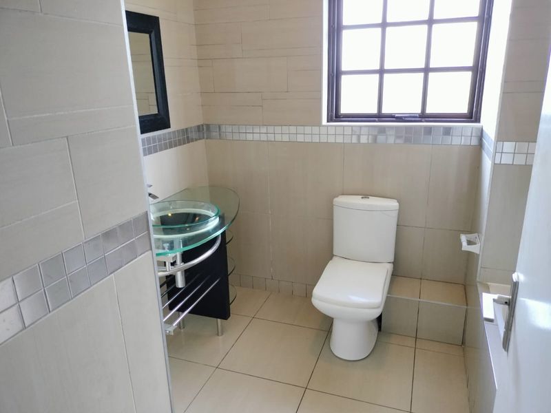 A functional bathroom featuring a glass vessel sink, vanity cabinet, and tiled finishes throughout.