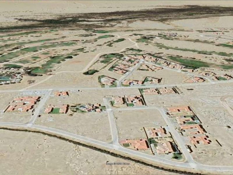 An aerial view of a residential estate development featuring multiple housing plots, internal road networks, and adjacent golf course landscaping.