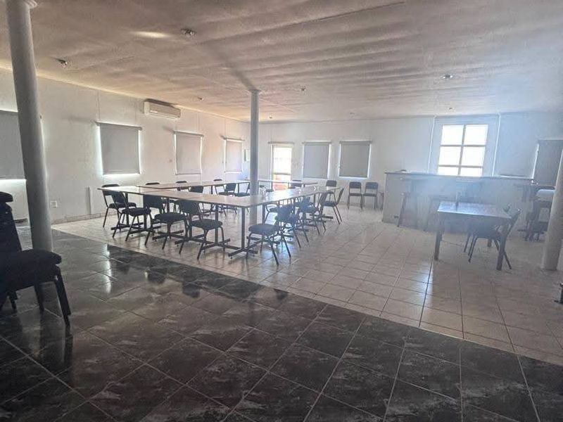 Spacious open-plan commercial area featuring tiled flooring, structural columns, built-in bar counter, and split-system air conditioning, suitable for various business configurations.