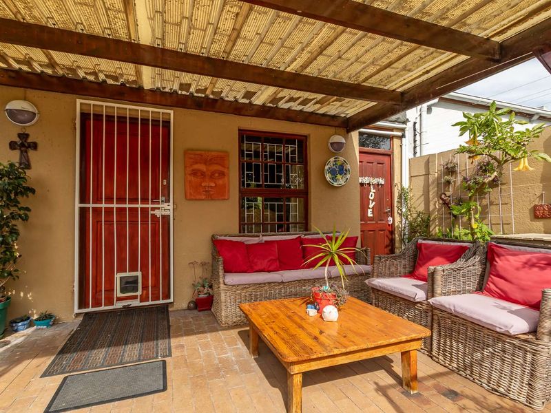 A covered outdoor patio area featuring brick paving, a timber pergola with polycarbonate roofing, and secure access points to the main dwelling.