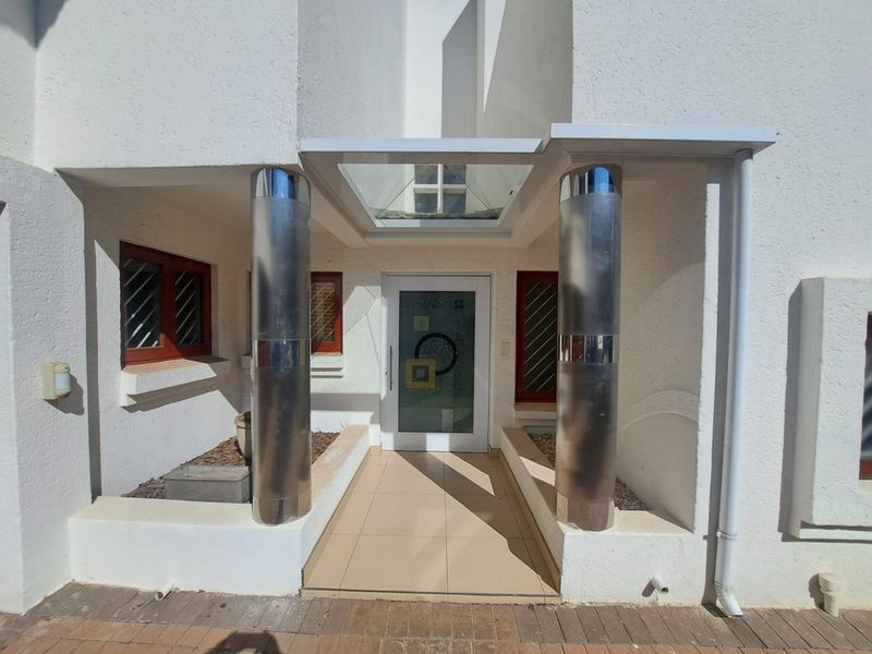 Front entrance featuring a glass canopy, stainless steel columns, and a decorative frosted glass door with tiled walkway.