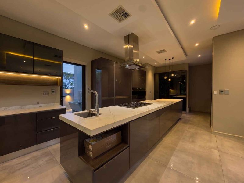 Modern kitchen featuring a large marble-topped island, high-gloss cabinetry, integrated appliances, and sophisticated recessed lighting in a spacious, contemporary layout.