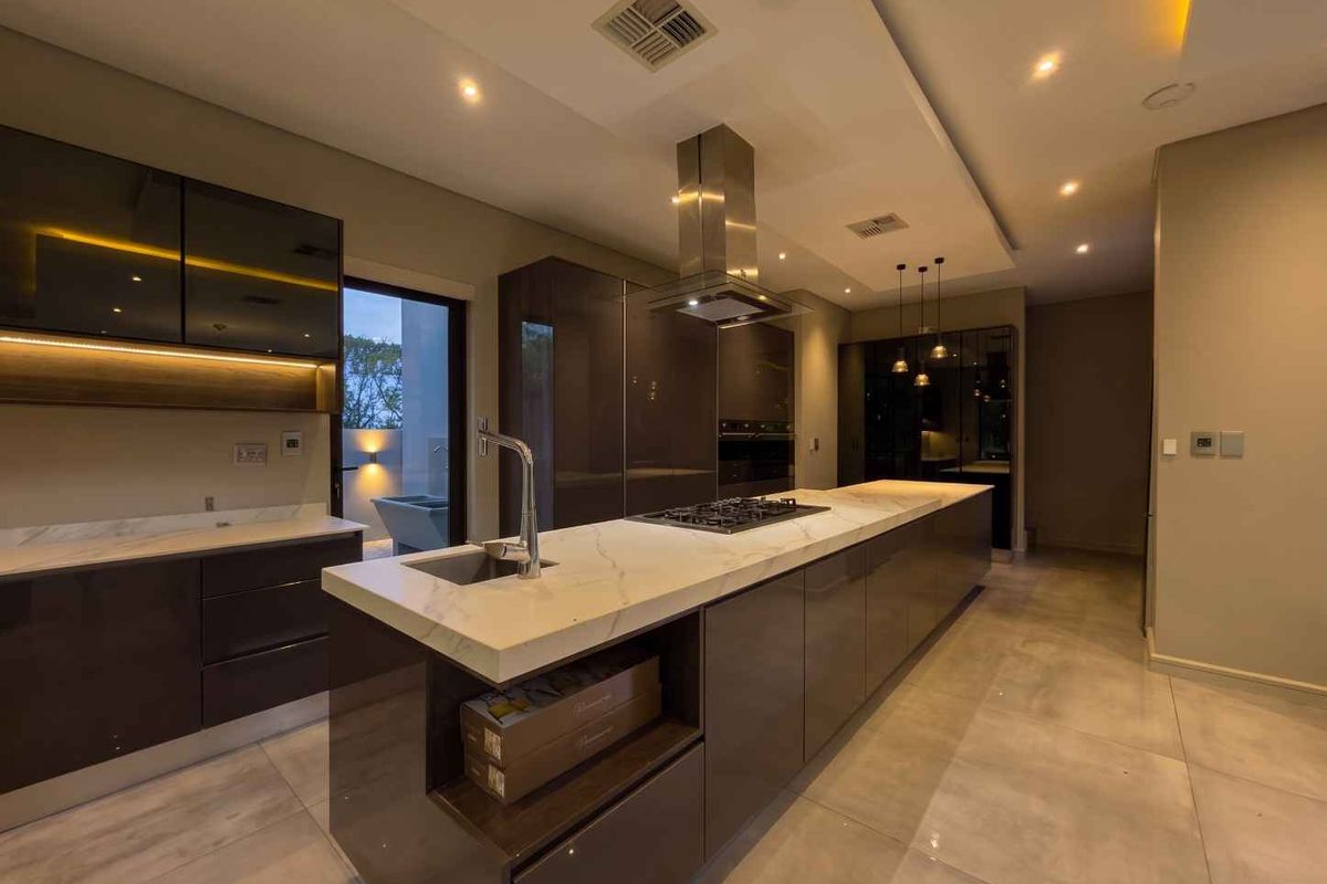 Modern kitchen featuring a large marble-topped island, high-gloss cabinetry, integrated appliances, and sophisticated recessed lighting in a spacious, contemporary layout.