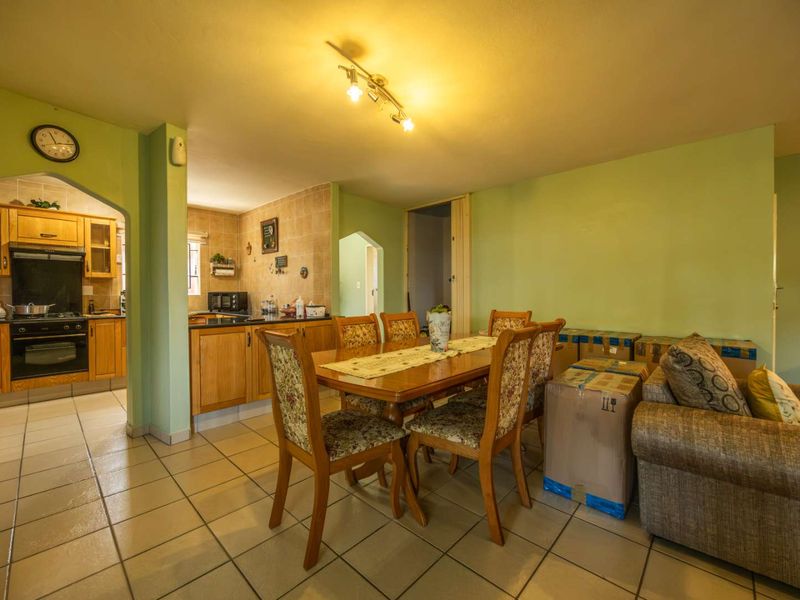 Open-plan living and dining area featuring tiled floors and an adjacent kitchen with wooden cabinetry, built-in oven, and hob.