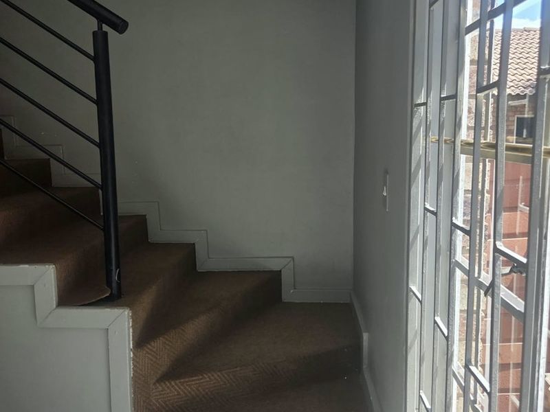 A staircase area featuring carpeted steps, a metal balustrade, and a large window with a security gate.