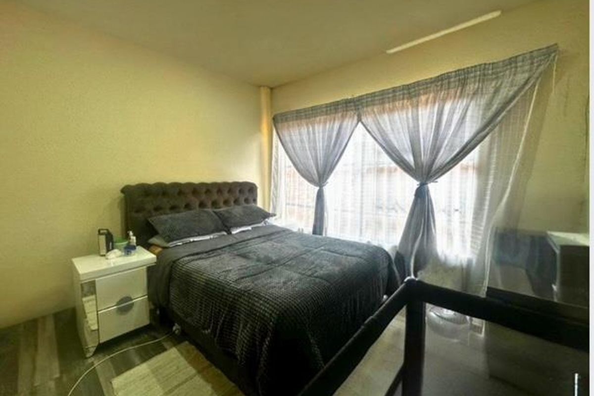 A bedroom featuring large windows with curtains and wood-look flooring.