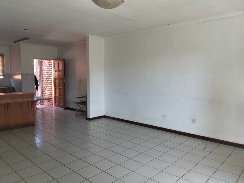 An open-plan living area featuring tiled flooring, a breakfast bar, and direct access to an exterior entrance.