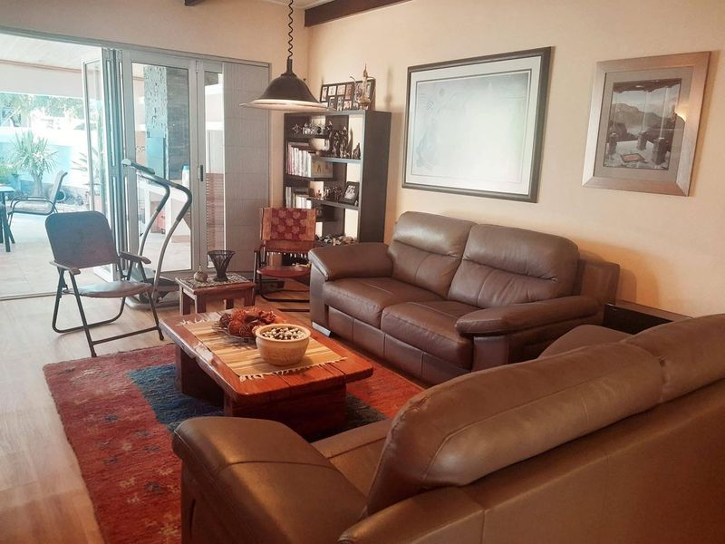 Comfortable living room featuring exposed timber ceiling beams and large sliding glass doors providing seamless access to the outdoor patio area.