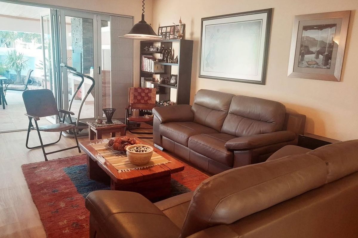 Comfortable living room featuring exposed timber ceiling beams and large sliding glass doors providing seamless access to the outdoor patio area.