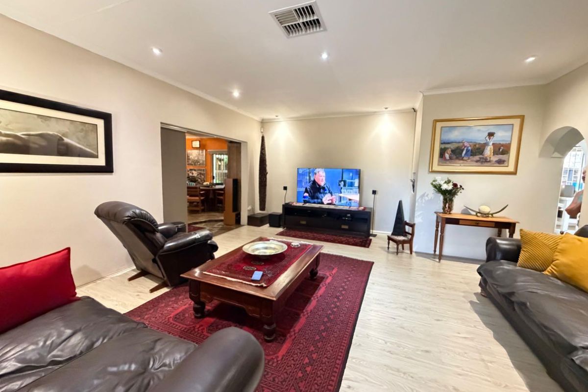 Spacious living room featuring light-toned laminate flooring, recessed downlighting, and central air conditioning vent, providing a comfortable and well-lit area for relaxation.