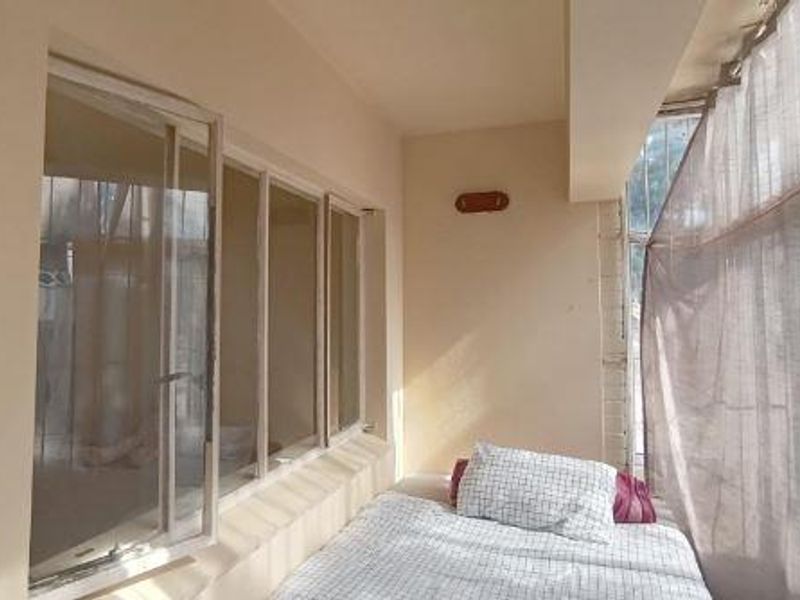 A covered balcony area featuring large casement windows and a wall-mounted light fixture, providing a functional outdoor space.