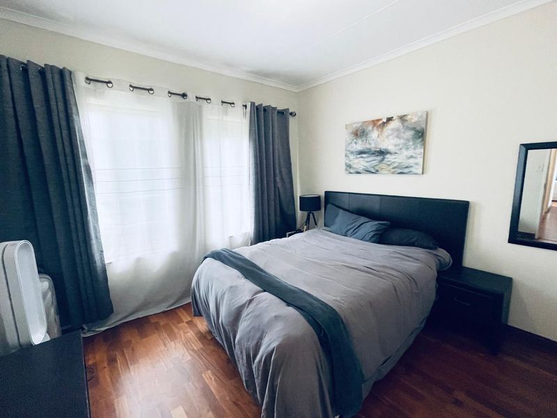 A well-maintained bedroom featuring warm-toned laminate flooring and neutral wall finishes, providing a comfortable and inviting living space.