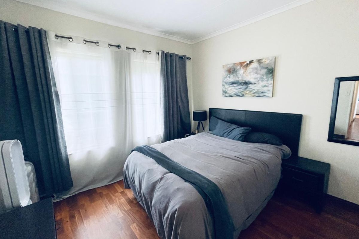 A well-maintained bedroom featuring warm-toned laminate flooring and neutral wall finishes, providing a comfortable and inviting living space.