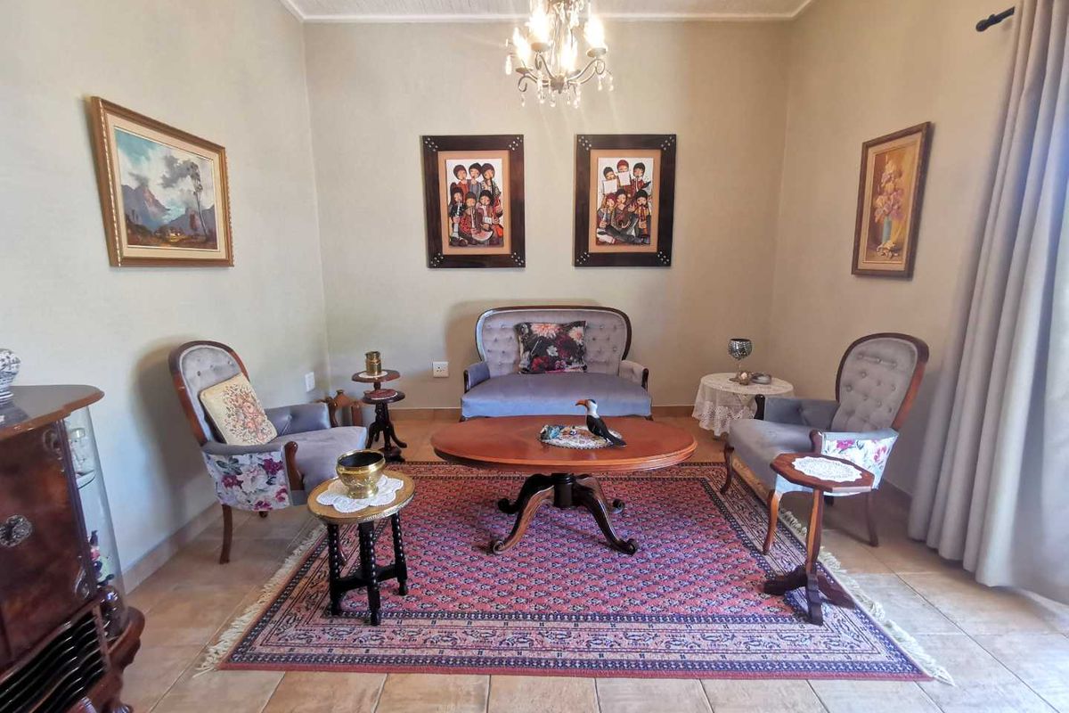 A formal living room featuring tiled flooring, a decorative chandelier, and neutral wall finishes, providing a classic and comfortable seating area.