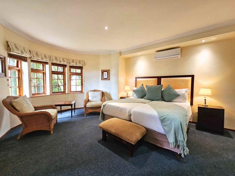Spacious bedroom featuring carpeted flooring, recessed downlighting, a split-system air conditioner, and a large bay window with timber frames.