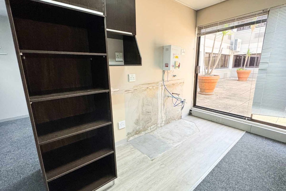 A small kitchenette area featuring built-in cabinetry, an electric water heater, and direct access to an outdoor patio through a sliding glass door.
