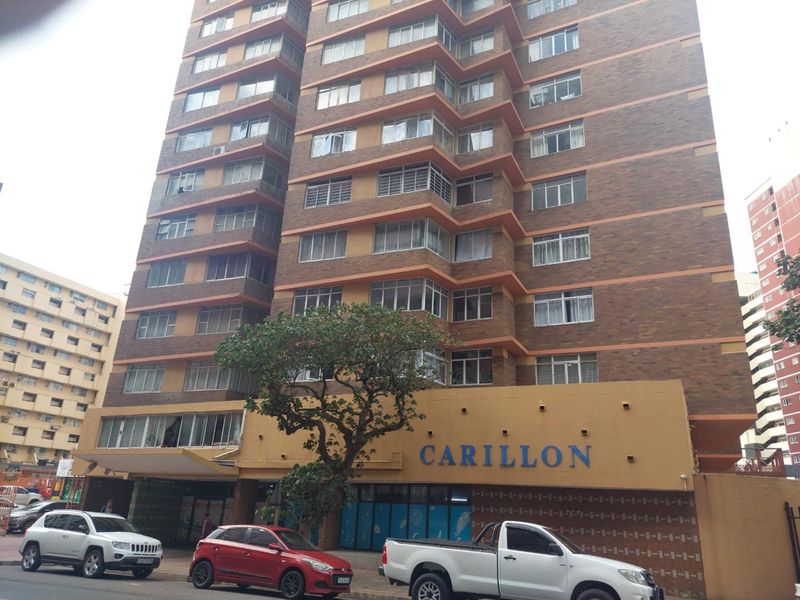 Exterior view of the Carillon apartment building, featuring a multi-story brick facade and ground-level entrance.