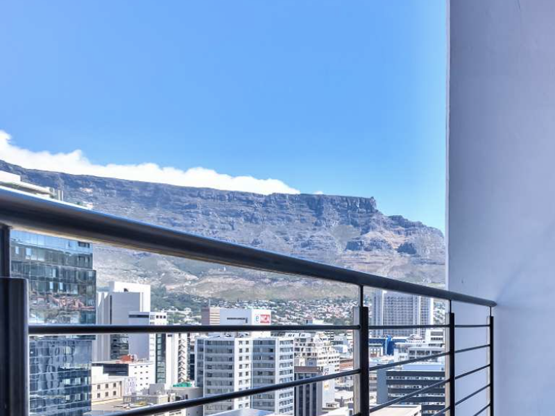 A clear elevated view of the city skyline and Table Mountain from a balcony with a modern metal balustrade.