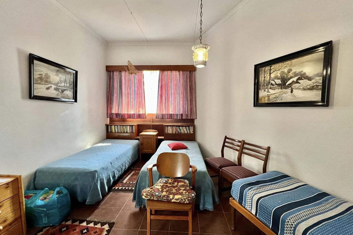 A bedroom featuring tiled flooring, a built-in wooden headboard with integrated shelving, and a central pendant light fixture.