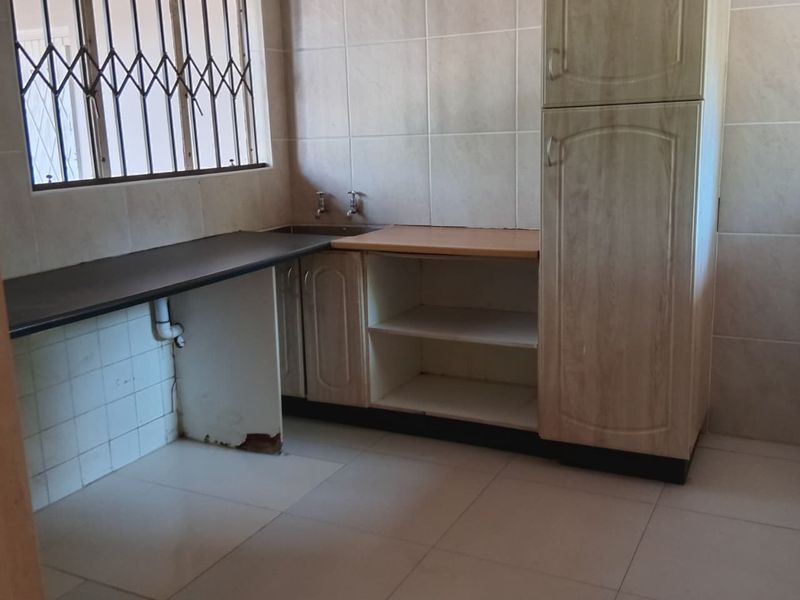 A functional scullery or utility area featuring built-in cabinetry, tiled surfaces, and plumbing connections, currently in need of minor repairs.